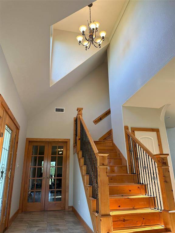 The grand foyer features high ceilings, a direct pathway to the office/extra bedroom, and a beautiful chandelier.