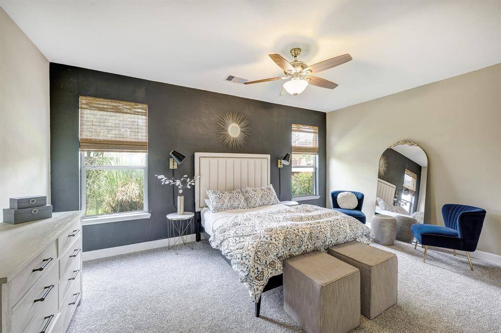 The primary bedroom has plenty of space. Note accent wall and large windows overlooking the backyard.