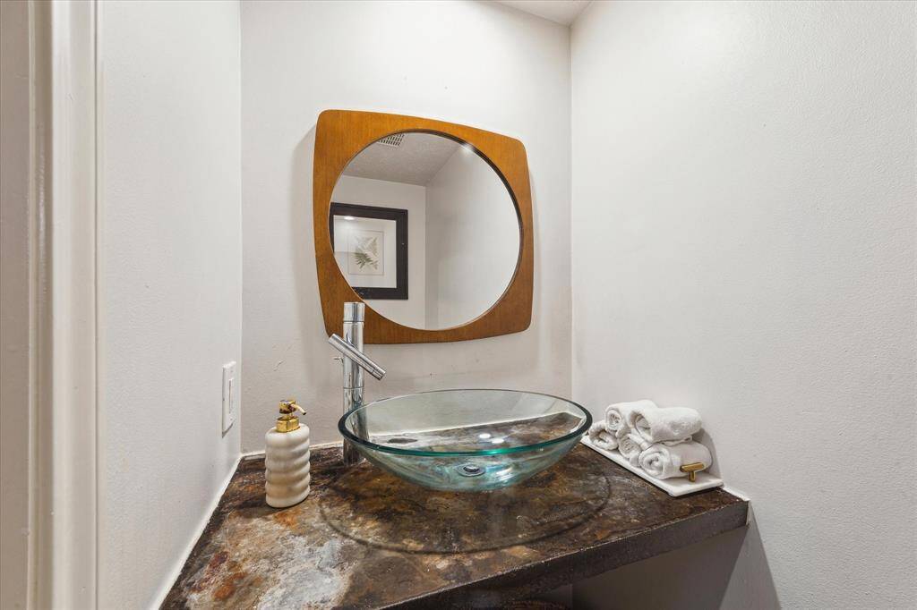 First floor half bath for your guests has a bowl sink and has a spa-like feel.