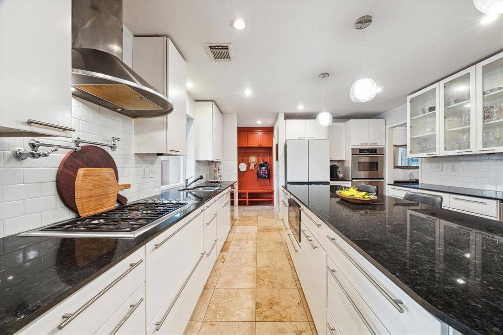 Stainless steel appliances include a double oven, stainless vent hood, five burner gas cooktop with a pot-filler, wine fridge and built-in microwave in the island.