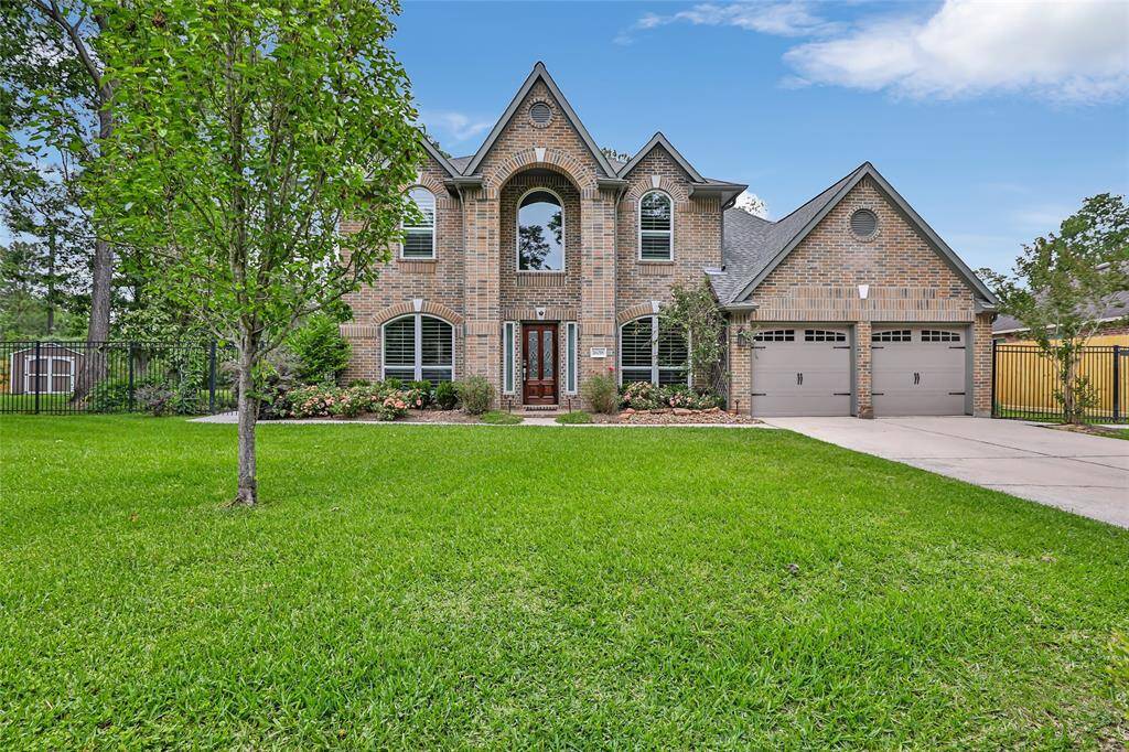 This stunning two-story brick home features a charming facade with arched windows and a welcoming entrance. It includes a spacious driveway leading to a two-car garage, and is surrounded by a beautifully maintained lawn and landscaped garden, set in a peaceful neighborhood.