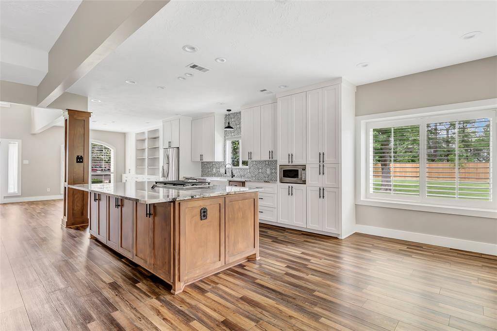 An inviting brick home entrance with a wooden door featuring decorative glass panels. The well-maintained landscaping includes vibrant flowers and shrubs, creating a warm and welcoming curb appeal.