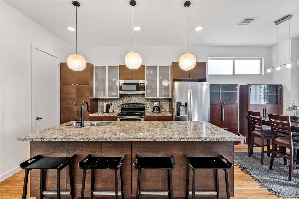 This modern kitchen features sleek stainless steel appliances, a convenient breakfast bar, and stylish light fixtures for a bright and inviting atmosphere.