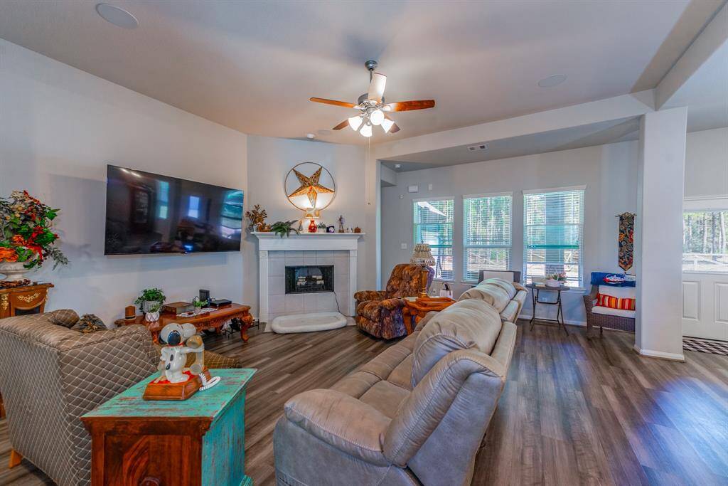 The spacious living room features a wood-burning fireplace, large windows with backyard views, and an open layout perfect for relaxing or entertaining.