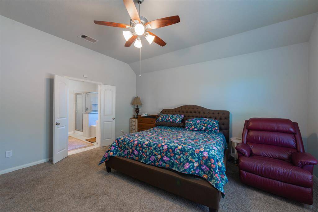 Spacious primary suite with high ceilings, plush carpeting, and double doors leading to the ensuite bath.