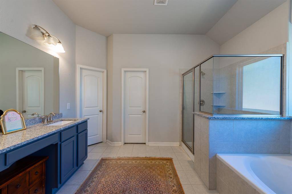The spa-like en-suite bath offers a glass-enclosed shower, a soaking tub, and a granite-topped dual vanity.