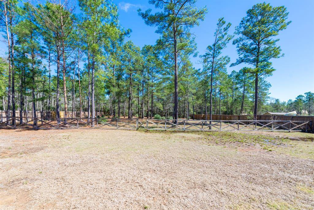 A split-rail fence separates the yard from the scenic wooded area, creating a peaceful and private retreat.