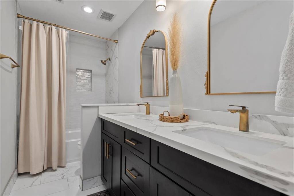 This secondary bath has been completely updated to include fresh gold hardware, quartz counters, and new cabinetry.