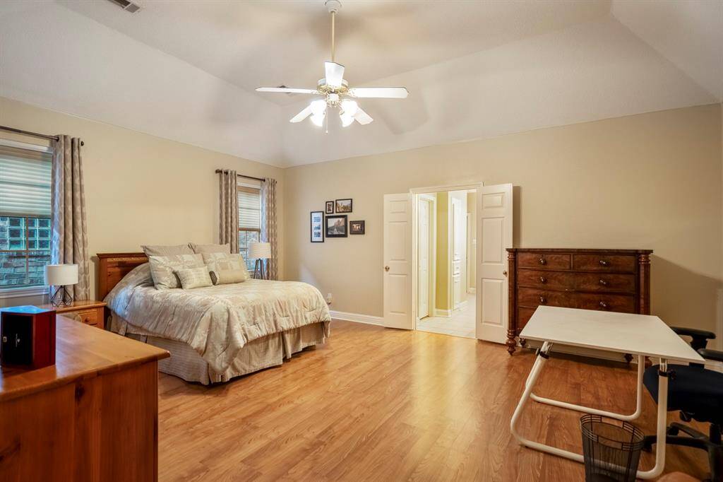 The primary bedroom, with vaulted ceiings, wood flooring, and room for a seating or work space if needed.