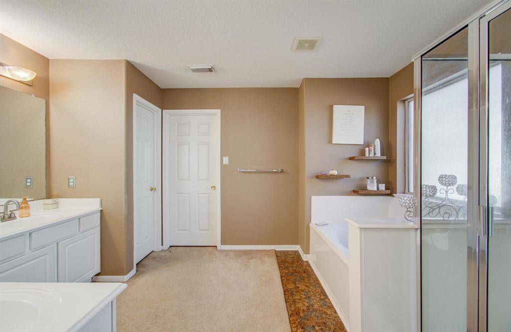 Very spacious primary bath with dual vanities, separate garden tub with stand-up shower enclosure.