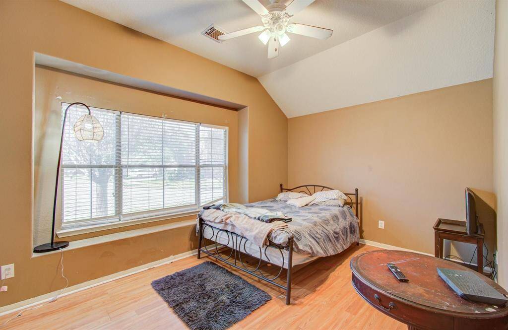 View of second spacious front bedroom with elevated ceiling and a good amount of windows that provide extra lighting, ceiling fan with light is also present.