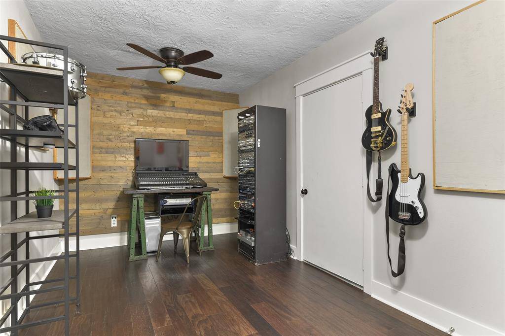 Beyond the bonus room in the previous picture, you'll find another bonus space that takes up one bay of the two-car garage. This room has been used as a music studio and features a lighted ceiling fan, engineered wood floors, and a wood plank accent wall.
