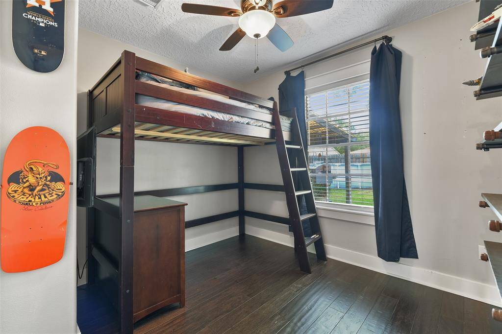 In another secondary bedroom, notice the neutral paint, lighted ceiling fan, backyard-facing window dressed with 2-inch blinds, and closet with built-in shelving and drawers.