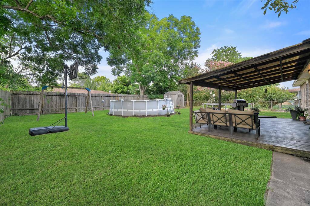 The backyard boasts a large covered patio area and an ample fenced yard. The above-ground pool that is visible in these photos has since been removed.