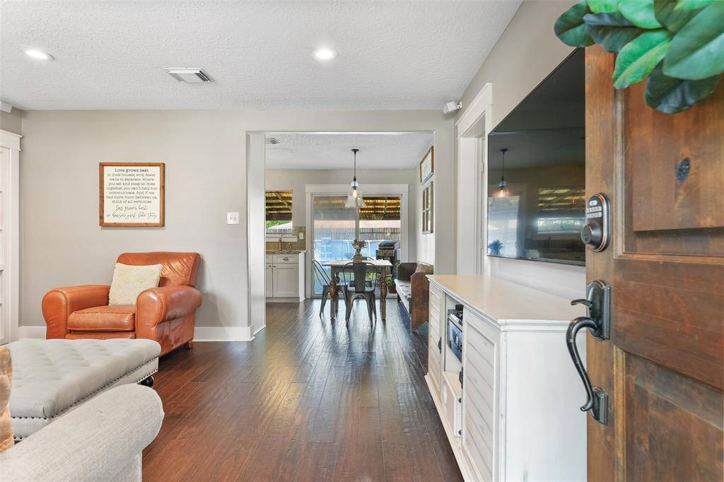 The carriage-style front door opens into a bright and airy open floorplan with handsome engineered wood floors, neutral grey paint, recessed lights, beautifully cased windows and doorways, and a built-in bookshelf with a little surprise behind it!