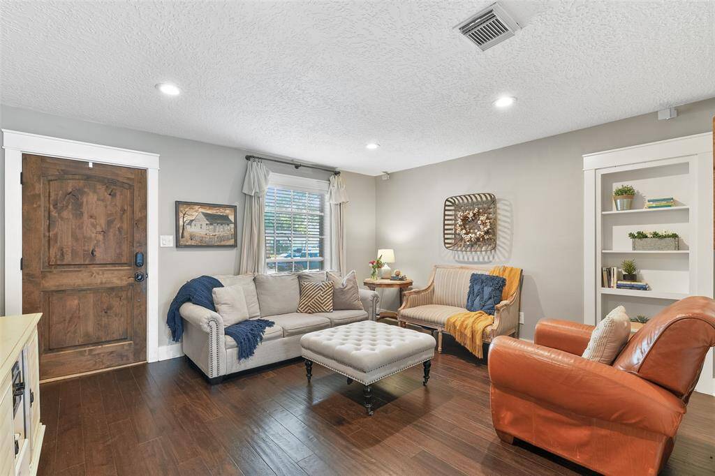 The carriage-style front door opens into a bright and airy open floorplan with handsome engineered wood floors, neutral grey paint, recessed lights, beautifully cased windows and doorways, and a built-in bookshelf with a little surprise behind it!