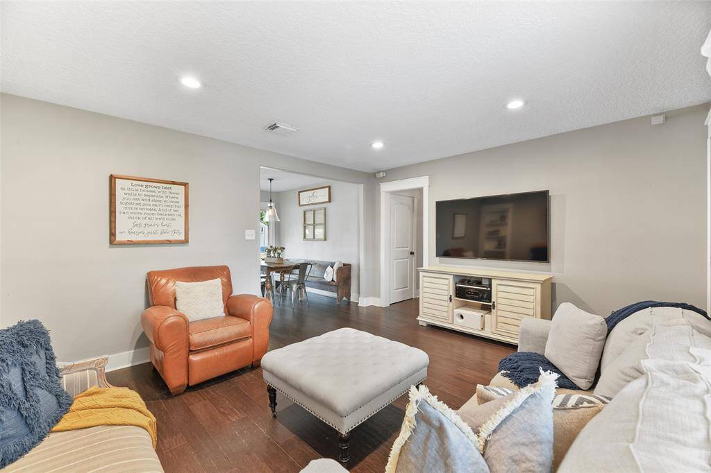 The carriage-style front door opens into a bright and airy open floorplan with handsome engineered wood floors, neutral grey paint, recessed lights, beautifully cased windows and doorways, and a built-in bookshelf with a little surprise behind it!