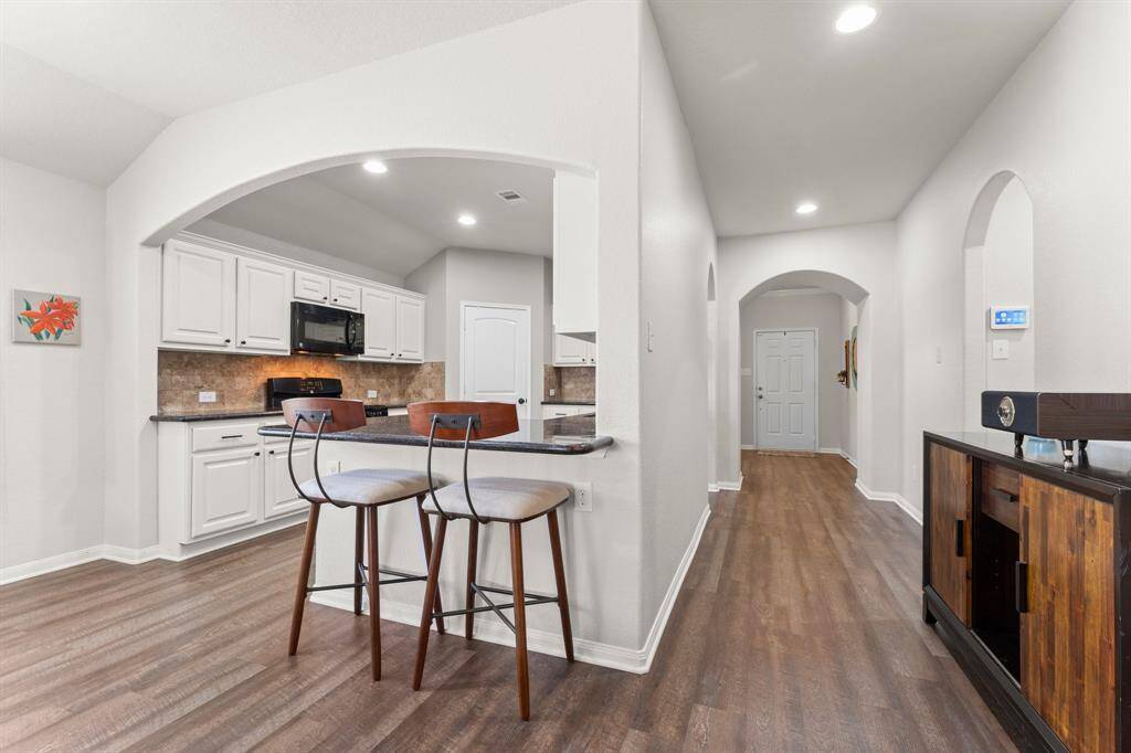 View showing the Kitchen in relation to the entryway and front door in the background.