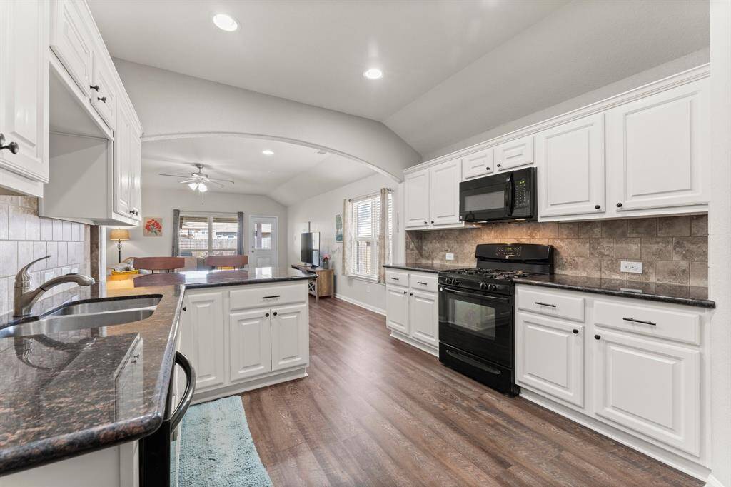 The kitchen features a gas range and oven, a mounted microwave, granite counters, and pulls on the cabinets.