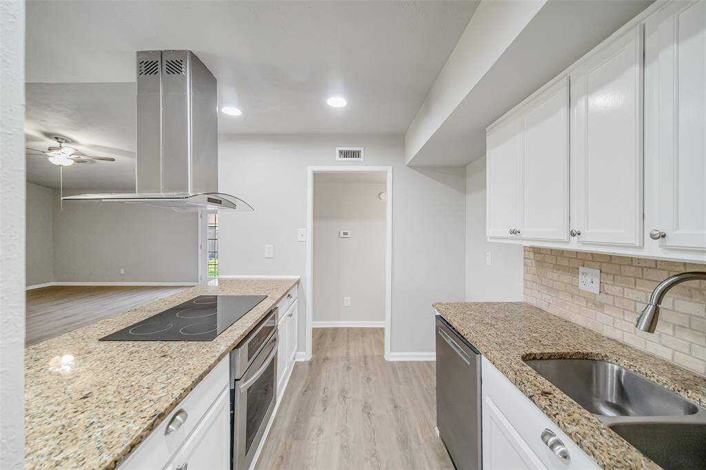 The beautifully updated kitchen features granite countertops, stainless steel appliances, a sleek vent hood, and freshly painted cabinets adorned with stylish knobs and drawer pulls.