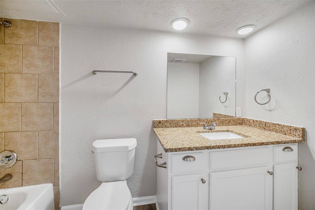 The secondary bathroom features a sink with granite countertops, cabinets with drawers, and a convenient combo shower and tub.