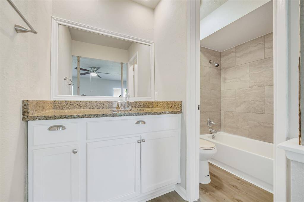 The primary en suite features a beautifully framed mirror, granite countertops, drawers and cabinets for your bathroom essentials, and a convenient combo shower and tub.