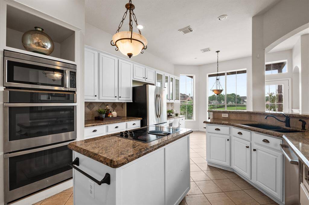The kitchen has stainless steel double ovens. The counter tops are granite and the backsplash is a neutral tile.