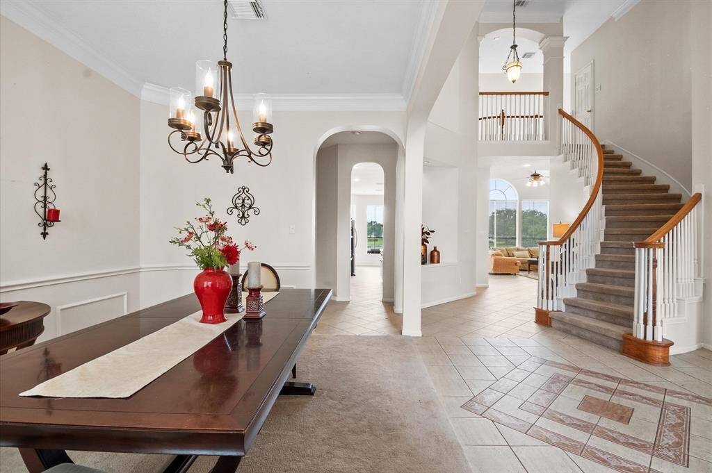 The entry features a two story ceiling with stacked art niches and an elegant, curved staircase. Flooring is tile from the front door through the family and the kitchen/breakfast areas.
