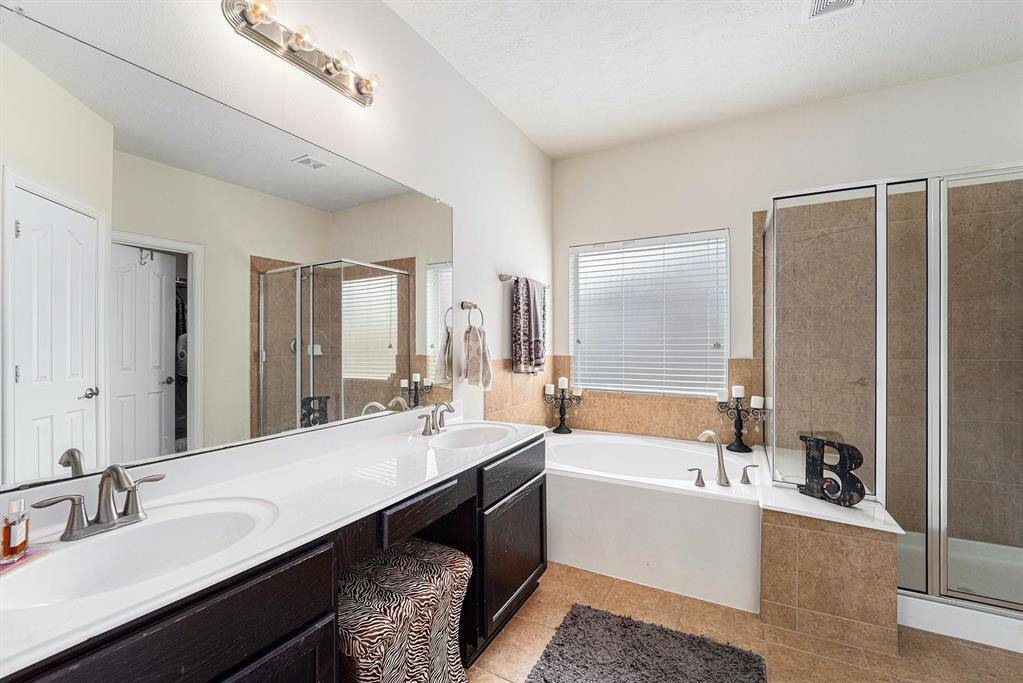 Lavish en suite showcases dual sinks, a soaking tub, a glass-standing shower, and a massive walk-in closet.