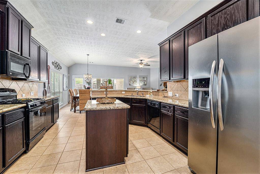 Chef's dream kitchen features ample countertop and cabinet space, a center island, and breakfast bar seating.