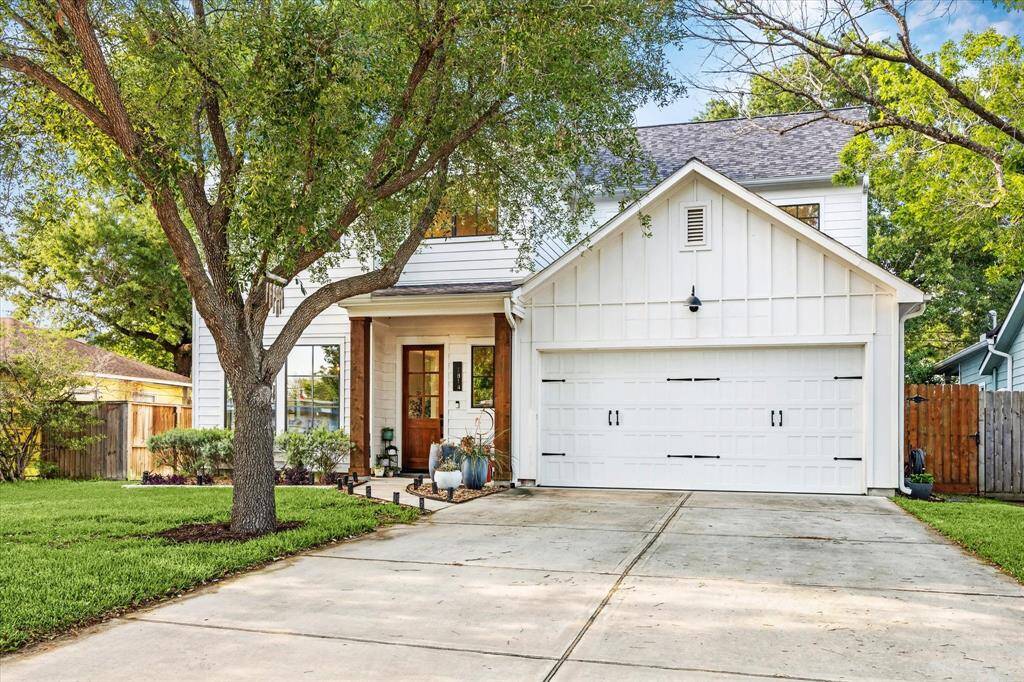 This charming home features a modern white exterior with a welcoming front porch and a two-car garage. The well-maintained yard has mature trees, providing shade and enhancing curb appeal.
