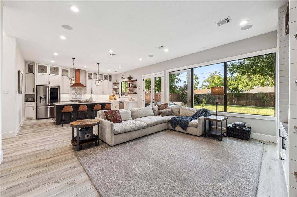 This photo showcases a modern butler's pantry with open shelving, a built-in wine fridge, and a sleek countertop leading into a bright dining area and walk-in pantry.