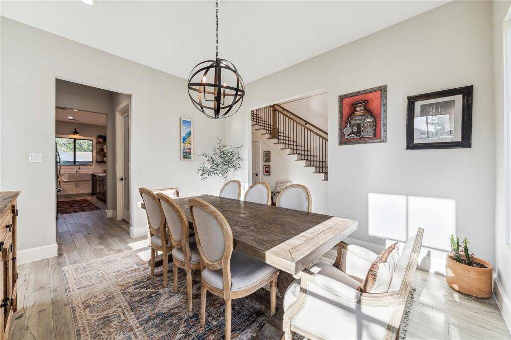 This bright entryway features a welcoming wooden door, elegant staircase, and light flooring.