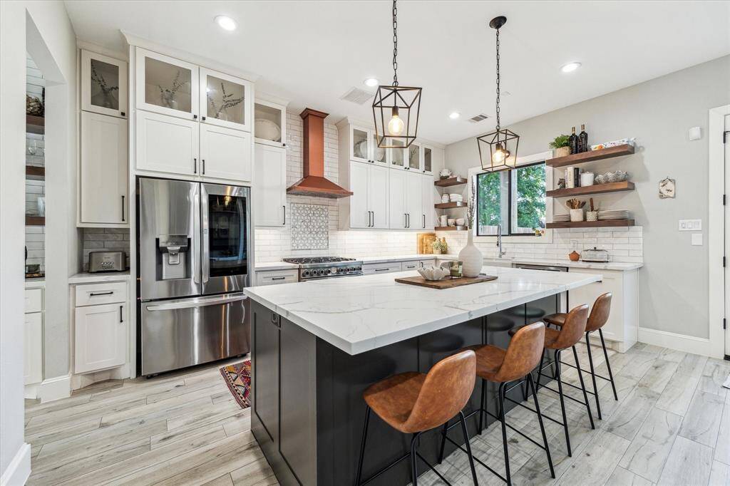 The dining room features a modern light fixture and large windows that let in plenty of natural light with a view of a kitchen and staircase, adding to the home's inviting layout.