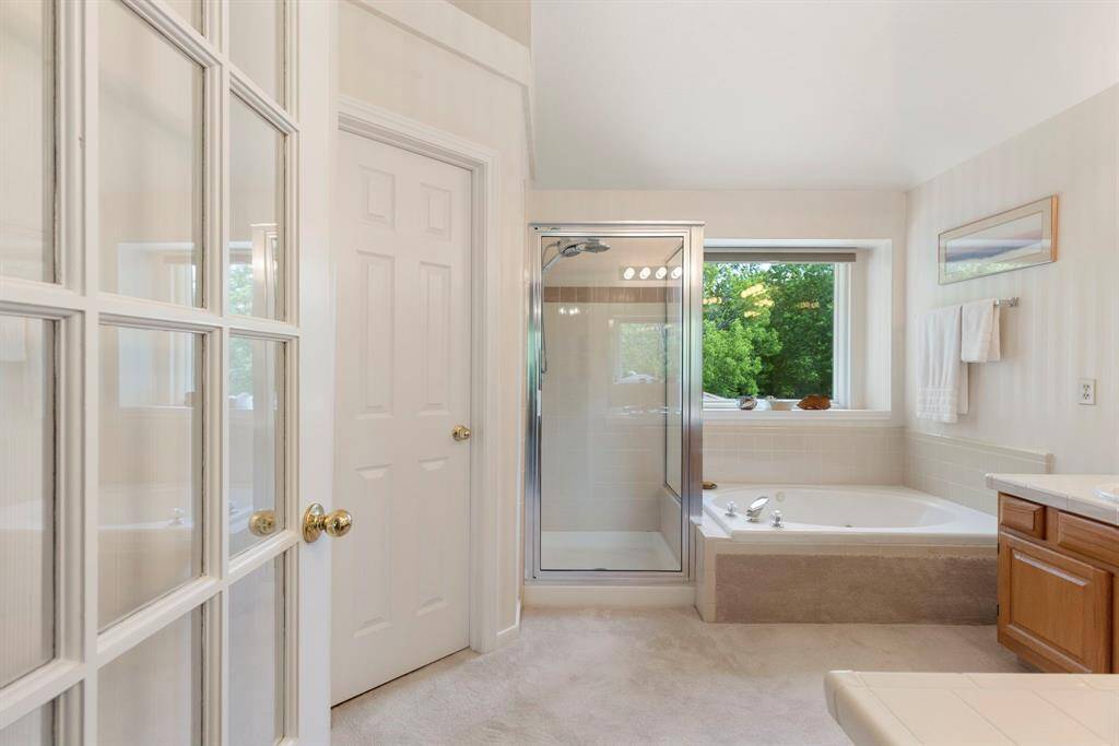 The primary bedroom offers an en-suite bathroom with neutral palette and abundant natural light.  Separate tub and shower with views of the mature trees in the back yard allow for a serene space to get ready in each morning.