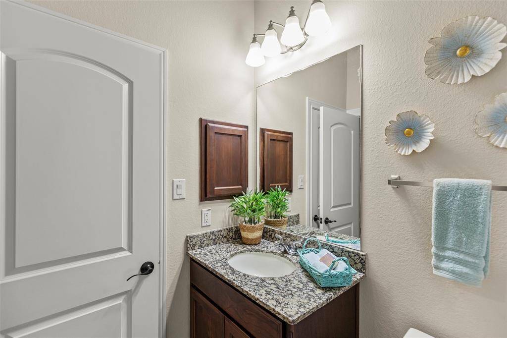 Cute Bathroom with Granite Countertop and a Cabinet, Mirror and Lovely Fixtures