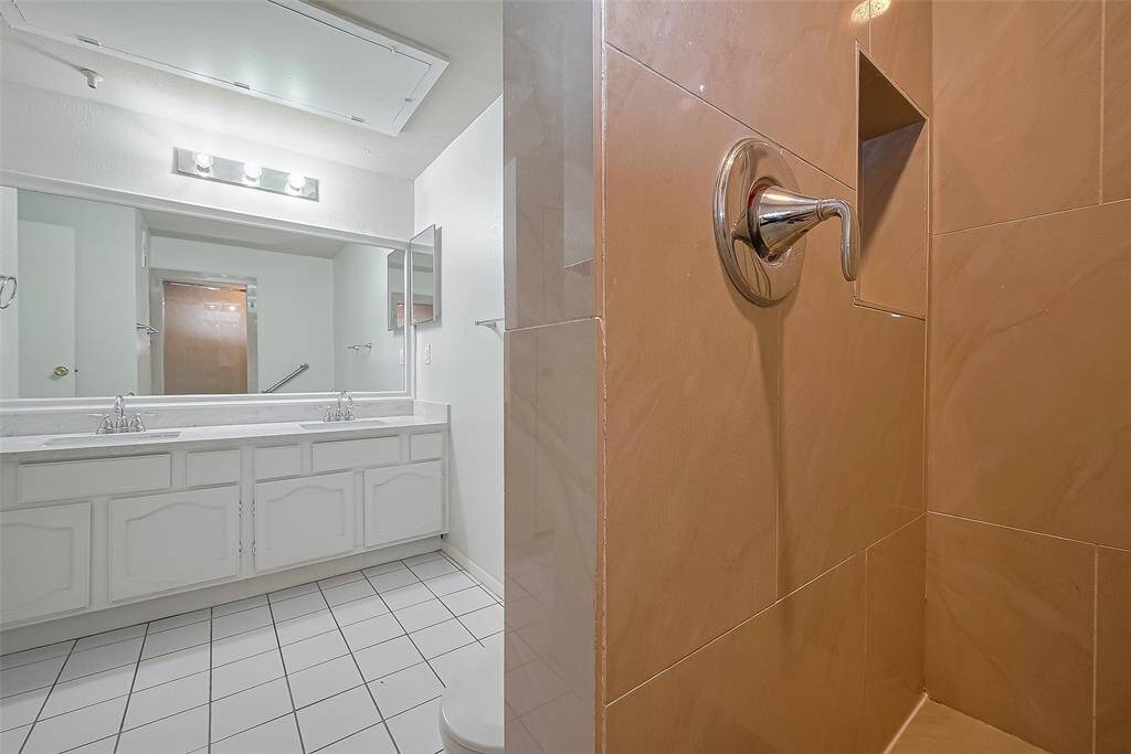The primary bathroom features a luxurious walk-in shower complete with a built-in shelf, perfect for keeping your essentials organized and within reach.