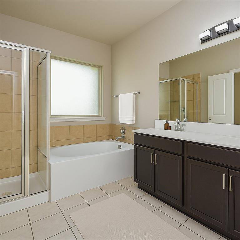 Spacious master bathroom featuring a sleek glass shower, inviting bathtub, and elegant dual vanities, perfect for relaxation and daily routines. Virtual staging was used.