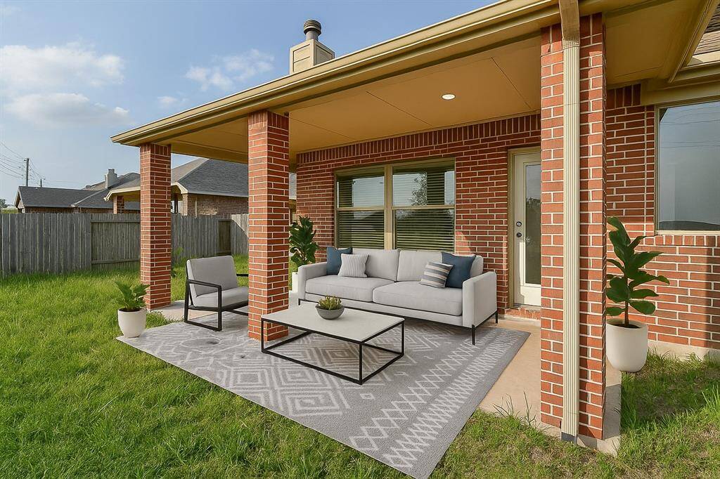 Relax and entertain on this inviting covered patio, featuring stylish brick columns, cozy seating, and lush greenery. Perfect for outdoor gatherings. Virtual staging was used.