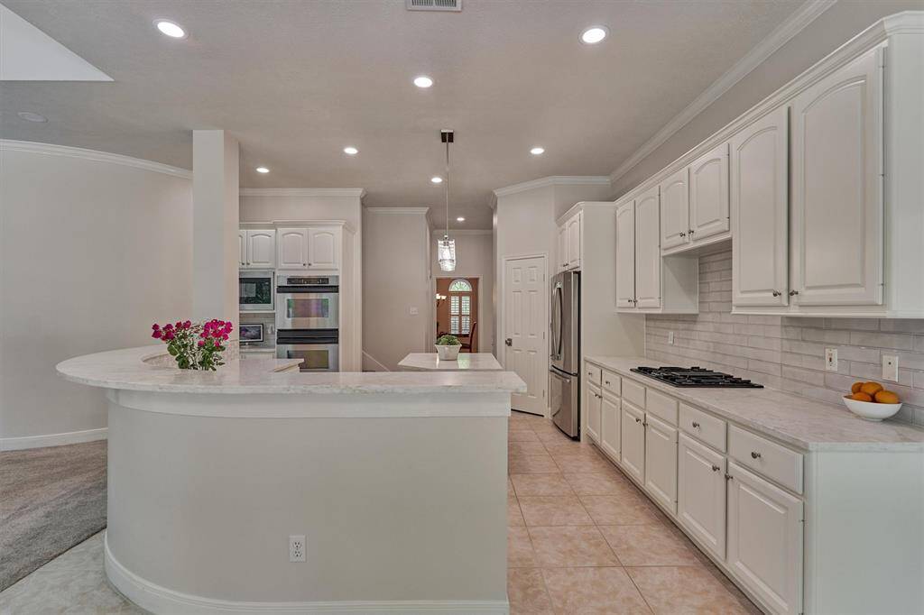 Beautifully updated with quartz countertops and hexagon-style backsplash. Note the abundant prep space, cabinet storage, double ovens and built-in microwave.
