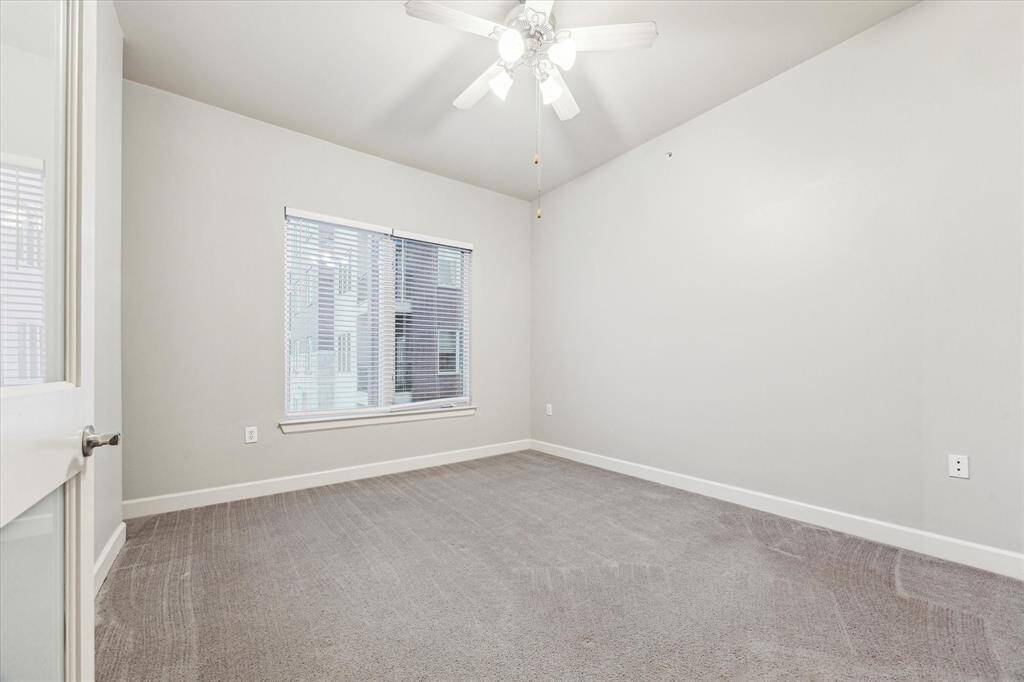 The spacious primary bedroom features neutral paint tones, plush carpeting, and a ceiling fan for year-round comfort—plus windows that offer relaxing views overlooking the pool.