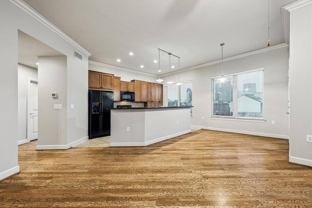 Bright and inviting open-concept living with warm wood floors, neutral paint, and oversized windows. Living room, breakfast area, and kitchen are seamlessly connected for effortless everyday living and entertaining.