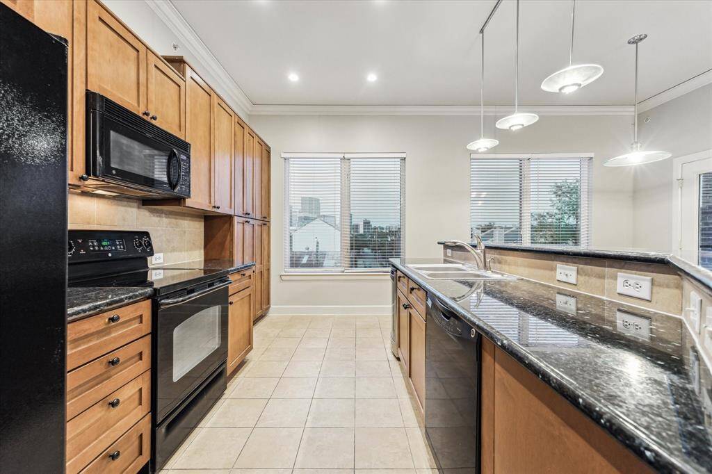 The kitchen features sleek granite, black appliances (including a matching refrigerator), complemented by a stainless steel sink and ample cabinetry for plenty of storage.