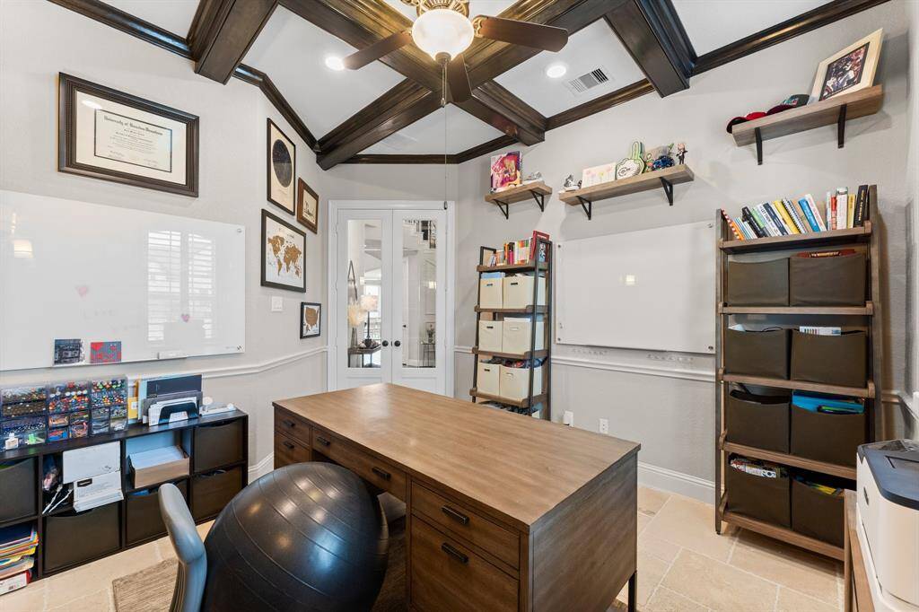 This photo showcases a home office with stylish exposed beams. The room has a clean, professional look with neutral tones and natural light from a window.