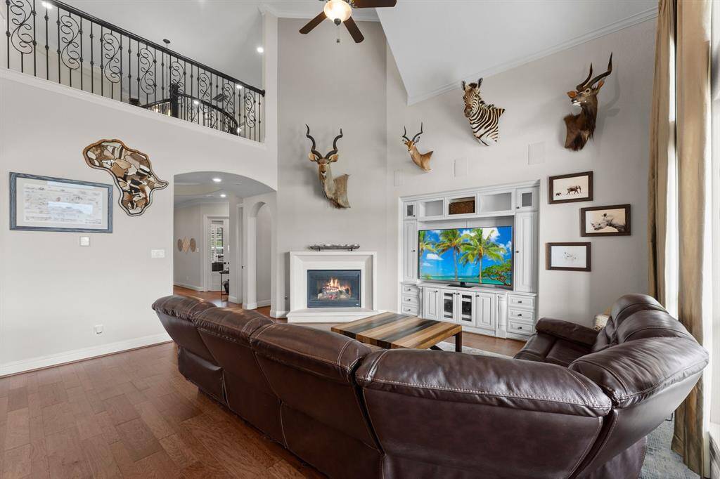 Spacious living room with high ceilings, featuring a cozy fireplace. A balcony overlooks the space, adding an open, airy feel.