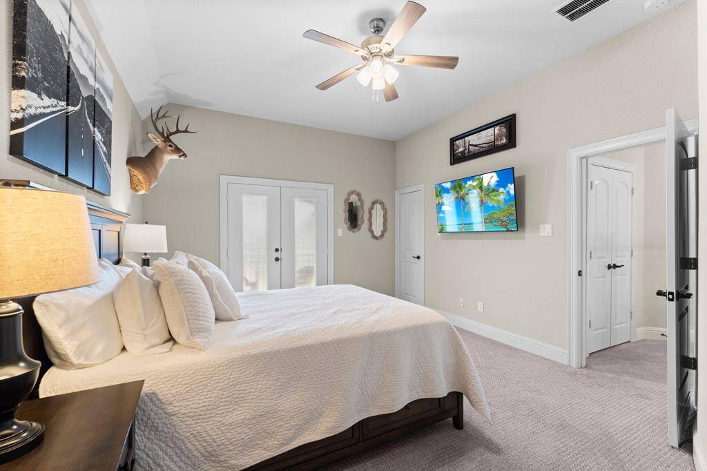 This cozy bedroom features double doors lead outside. The room is well-lit, offering a comfortable and inviting atmosphere.