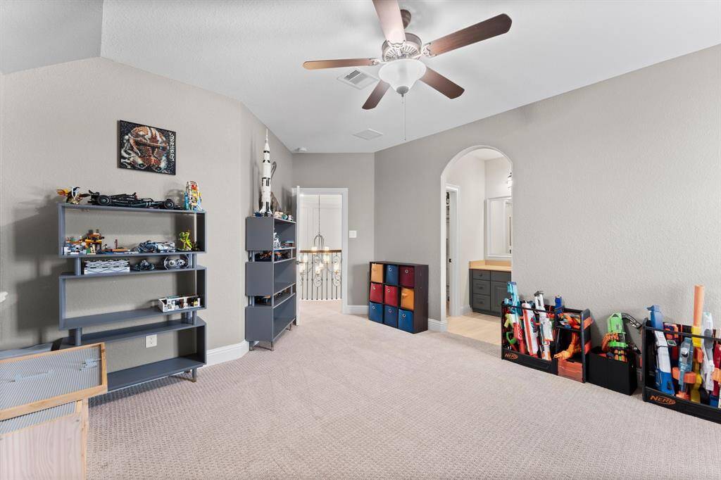 This spacious, bedroom features a ceiling fan, and an arched doorway leading to a bathroom.