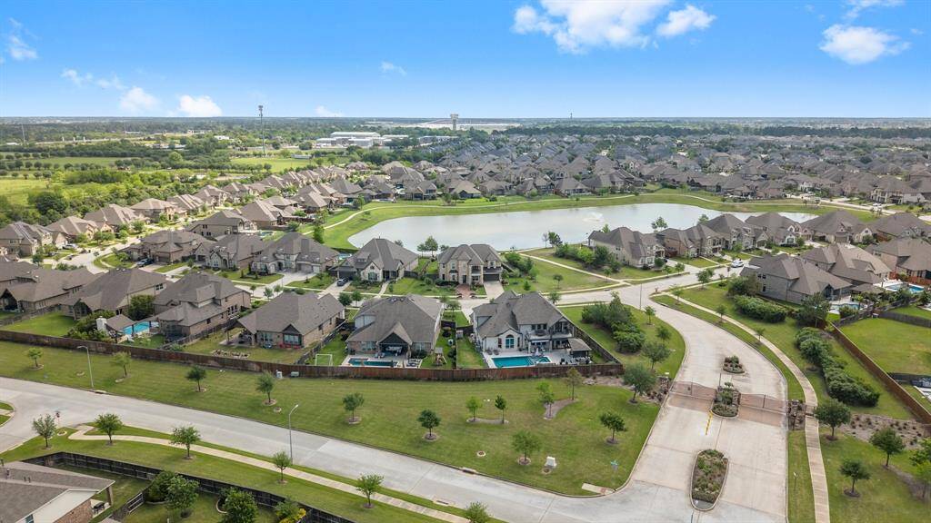 This aerial photo showcases a suburban neighborhood with well-maintained homes, lush greenery, and a central lake.