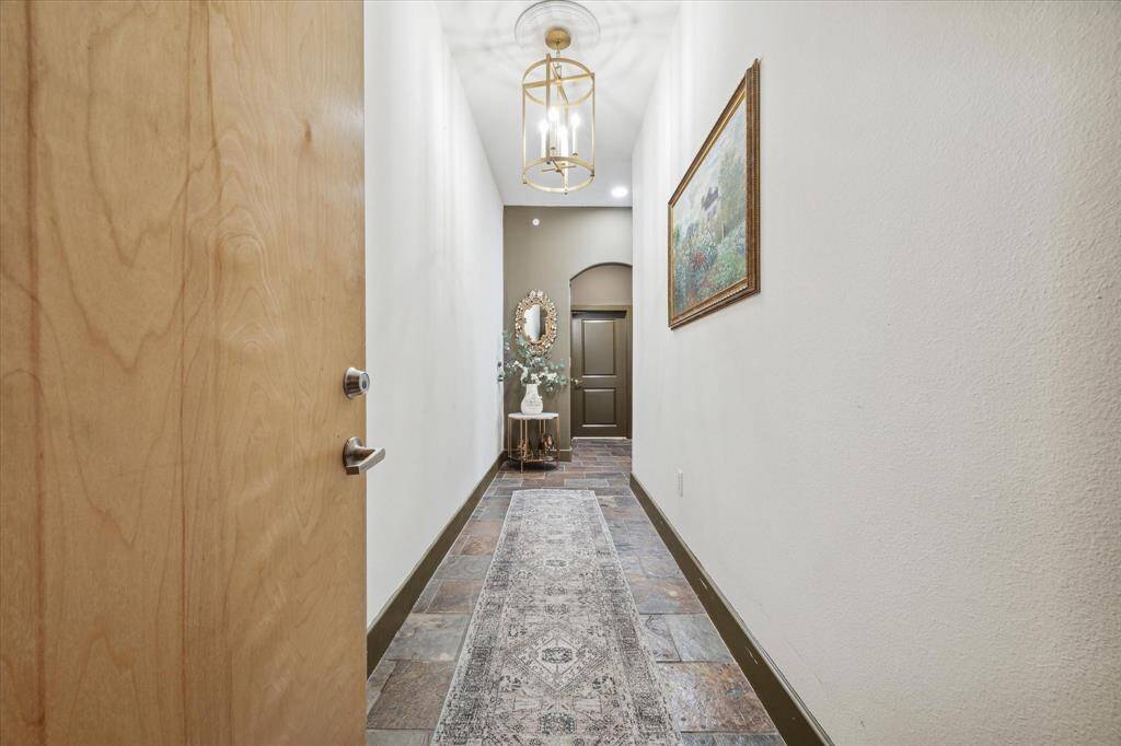 This is a well-lit, elegant hallway featuring a high ceiling with a stylish light fixture is very welcoming.