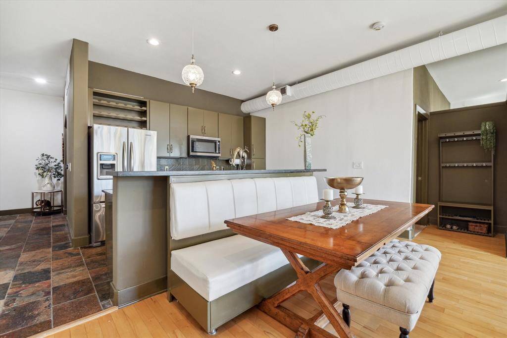 Open-concept kitchen and dining space featuring modern appliances, sleek cabinetry, and a mix of tile and hardwood flooring. The breakfast bar and cozy dining area provide a comfortable space for meals and gatherings.